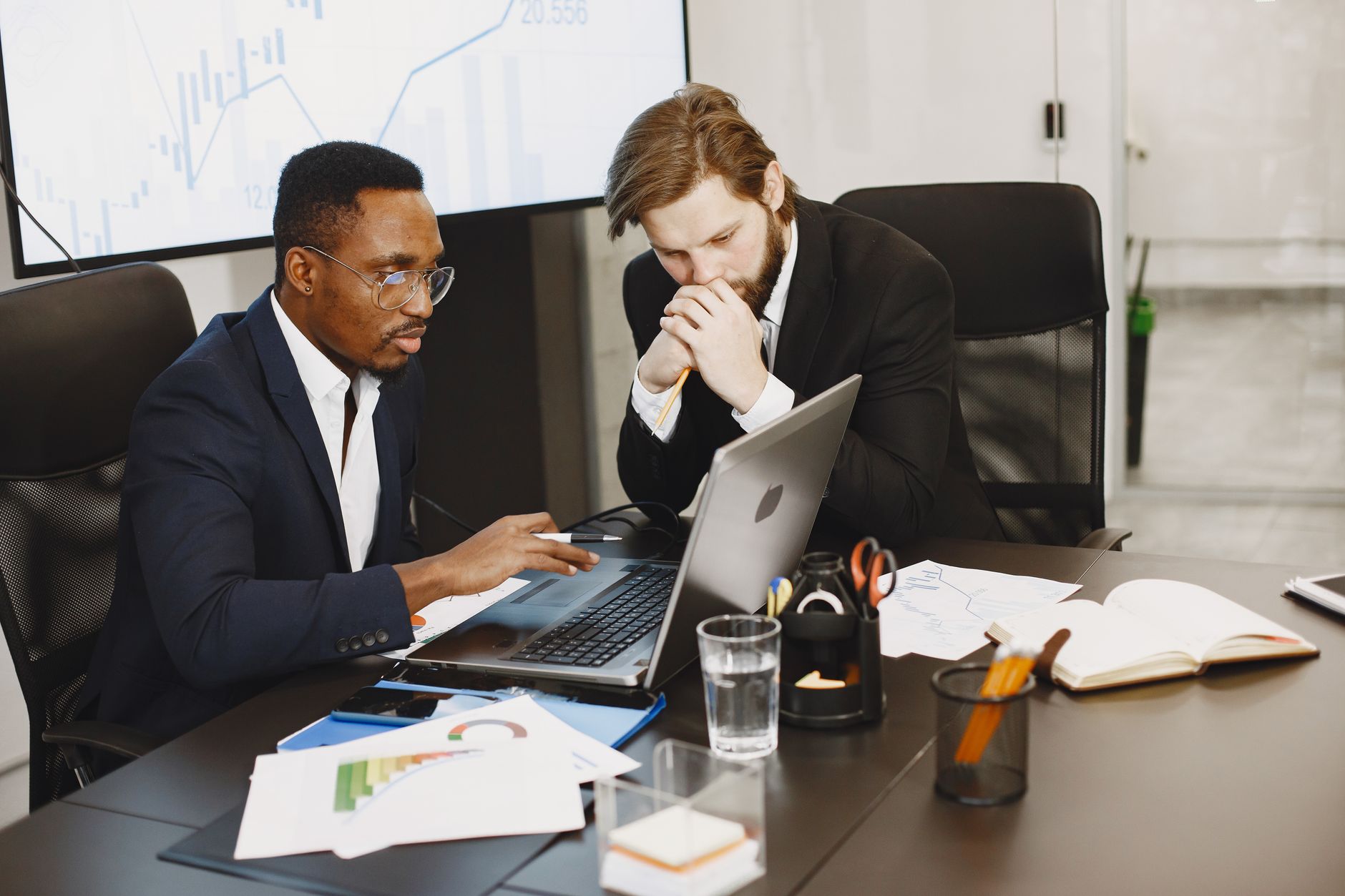 Two businessmen engaged in a strategy meeting with laptops and charts. — A Perfect Meal Awaits You at the Steak House Restaur