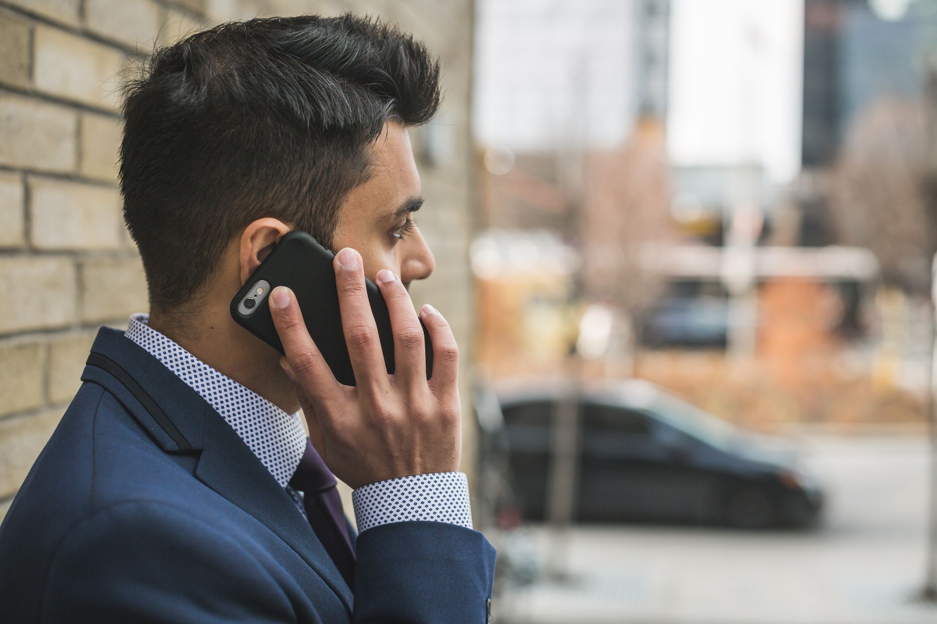 Professional man in suit making a phone call outside in city setting. — Dr. Azfar Malik Supporting Innovation in Mental Healt