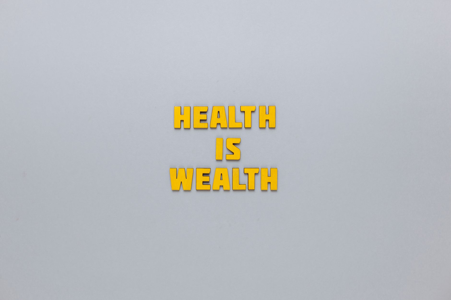 Inspirational phrase 'Health is Wealth' in bold yellow letters on a neutral gray background. — How to Safely Buy Testosterone