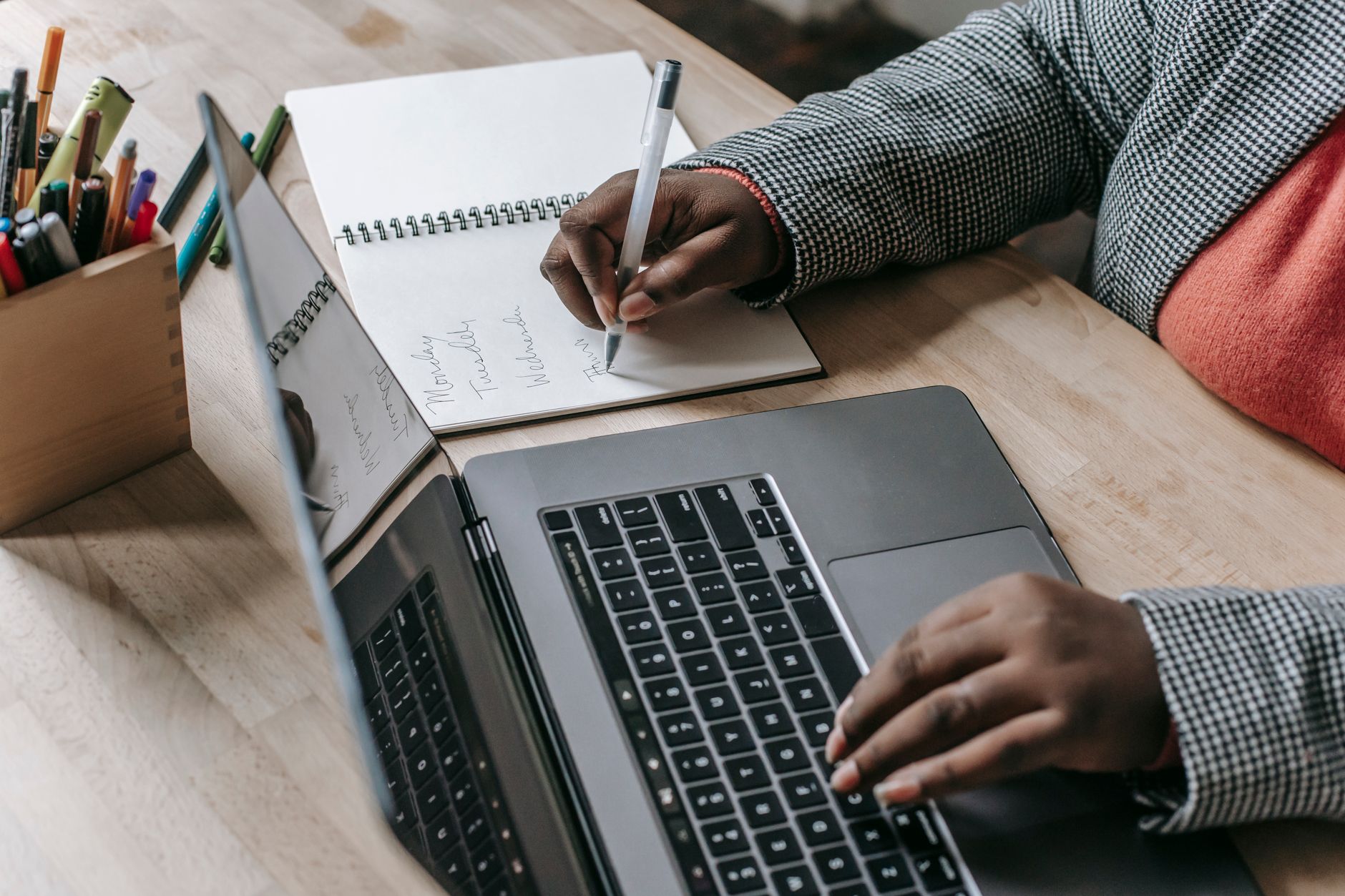 Crop unrecognizable African American female in formal wear writing notes in notepad while working on laptop — Steel City Secu