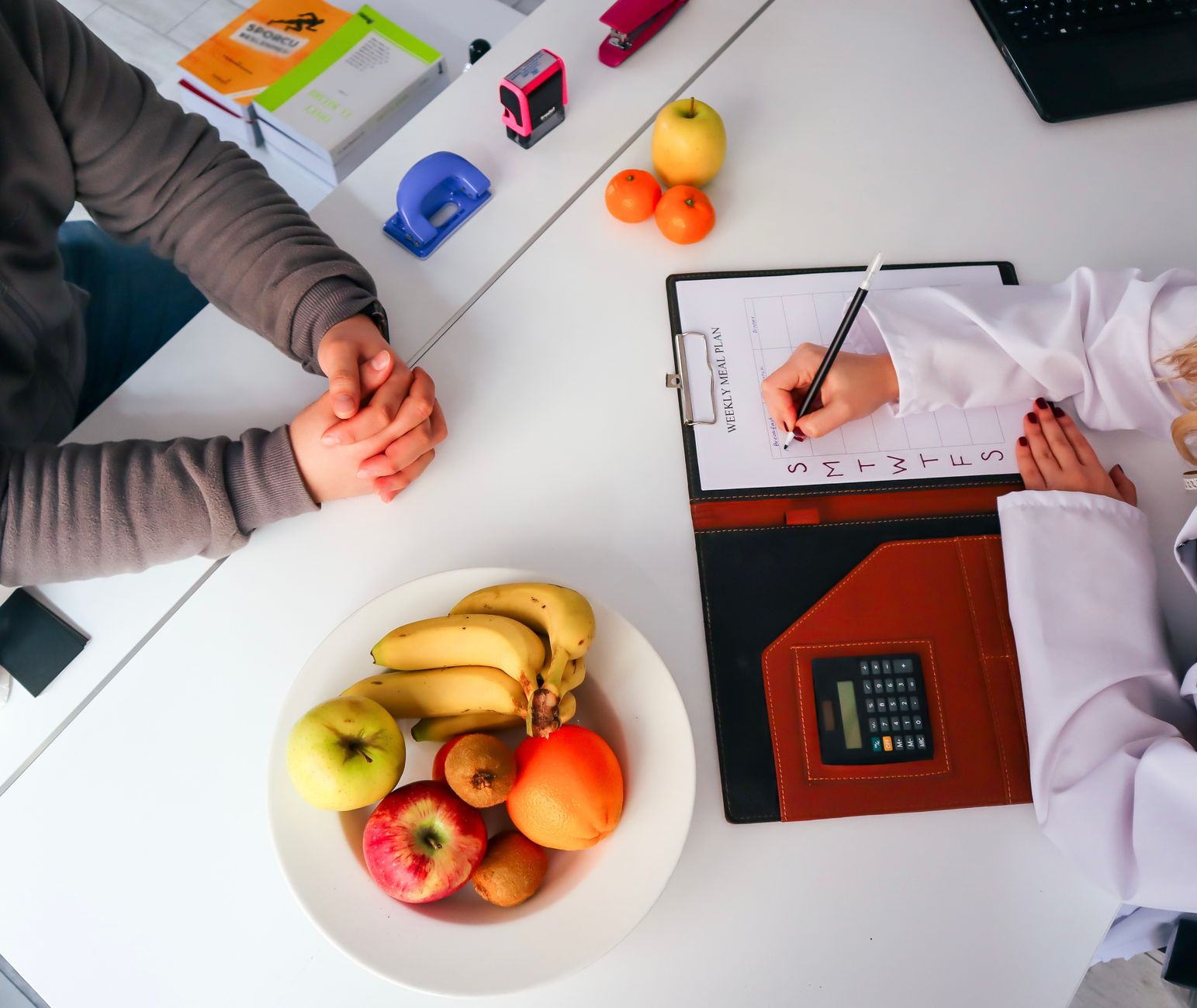 Top view of a dietitian planning a healthy diet with fresh fruits on the table, focusing on health and nutrition. — The Vital