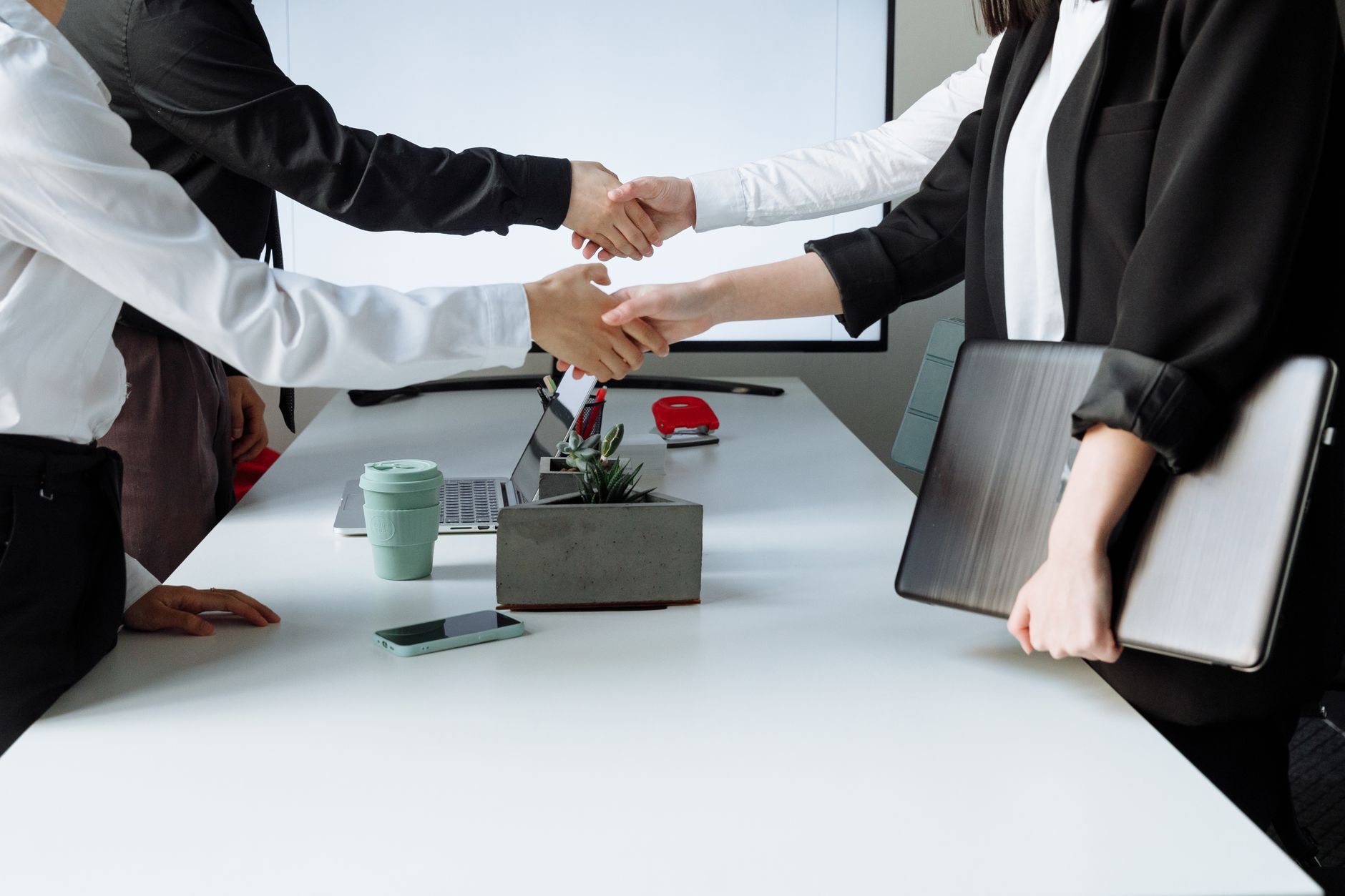 Professionals sealing a deal with a handshake across a conference table during a business meeting. — Trusted Experts for Wind